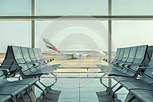 Barcelona, Ã¢â¬â¹Ã¢â¬â¹Spain - March 17, 2019: Empty chairs in the departure hall at airport on background of airplane taking off.